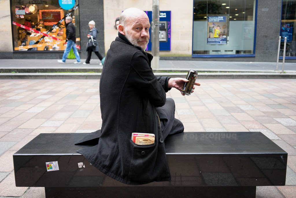 Man sitting on a bench, drinking on Sauchiehall Street, Glasgow, Scotland