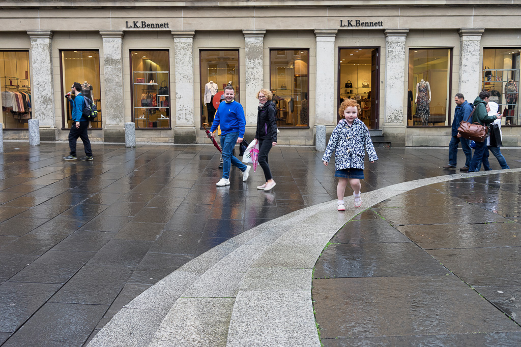 Child runs in the rain at the Royal Exchange Square, Glasgow, Scotland