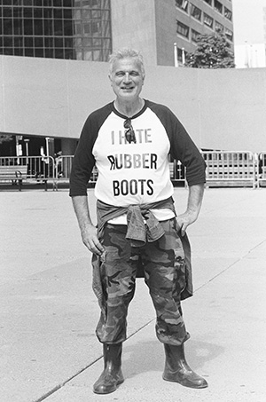 Man wears "I Hate Rubber Boots" T-shirt in Nathan Phillips Square, Toronto.