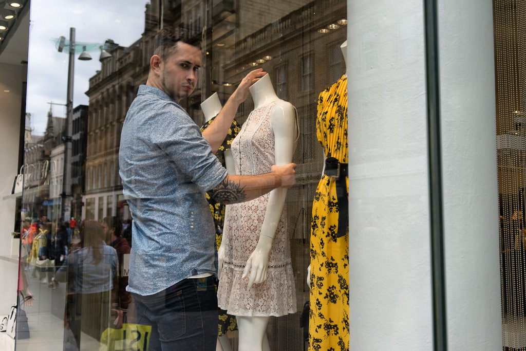 Man adjusts a mannequin in a shop window on Buchanan Street, Glasgow