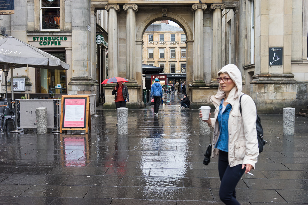 Woman with cup of coffee & cigarette walks through the Royal Exchange Square, Glasgow