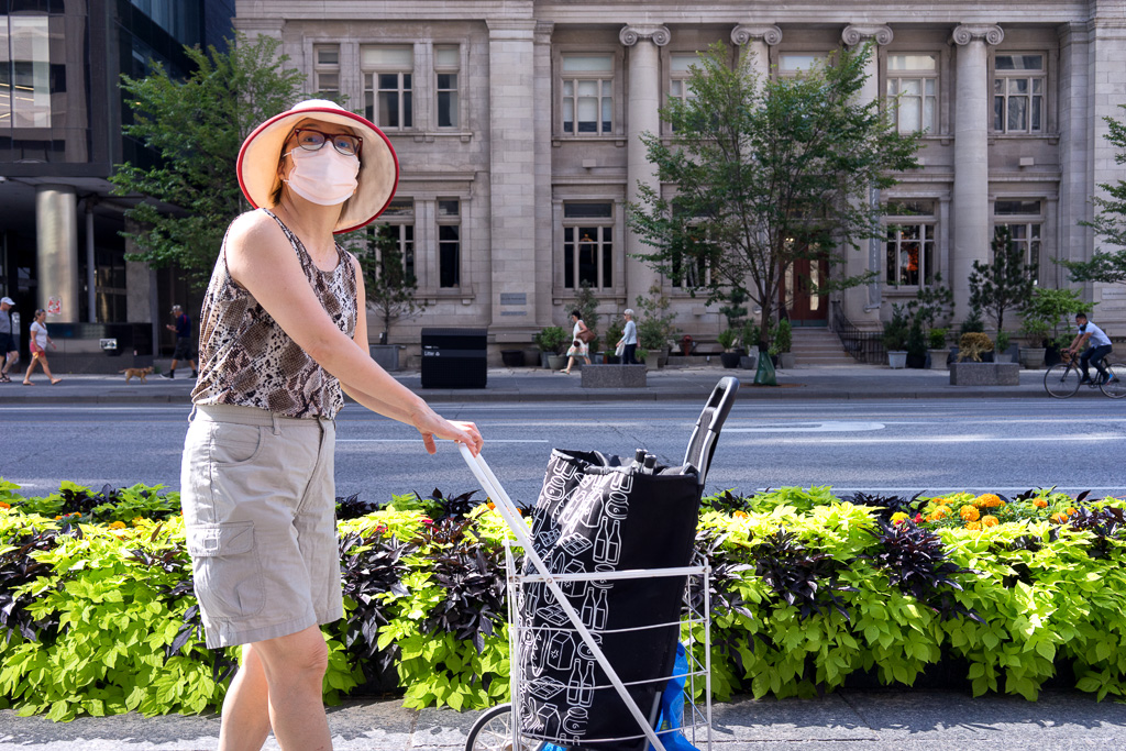 Woman pushes bundle buggy along the sidewalk on Toronto's Bloor Street West.