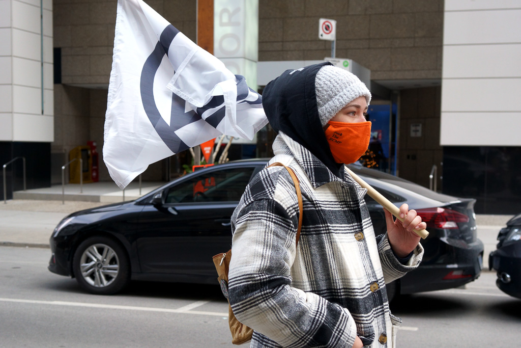 A protester carrying a flag blocks Bloor Street East between Sherbourne & Huntley, Toronto