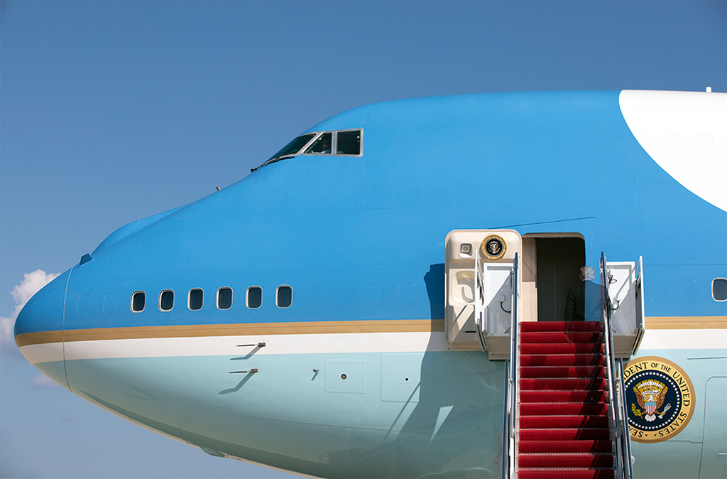 A vanishing Donald Trump climbs the stairs to board Air Force One.