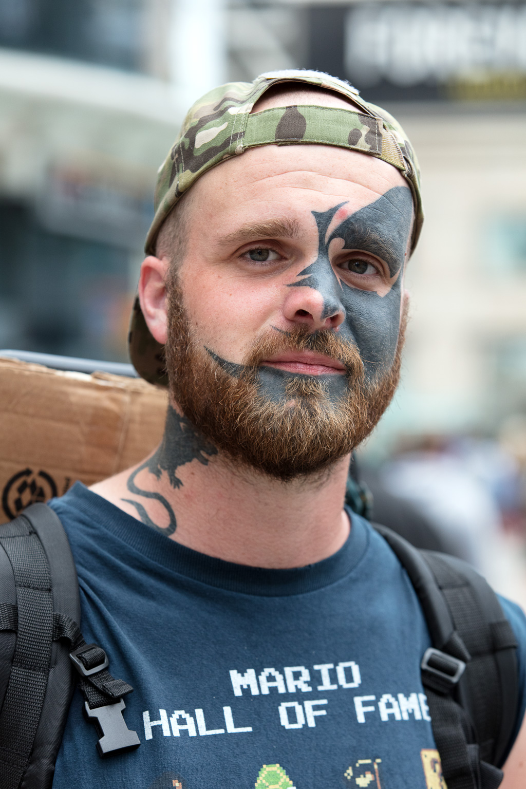 Man wearing backward baseball cap and with tattoo on his face.