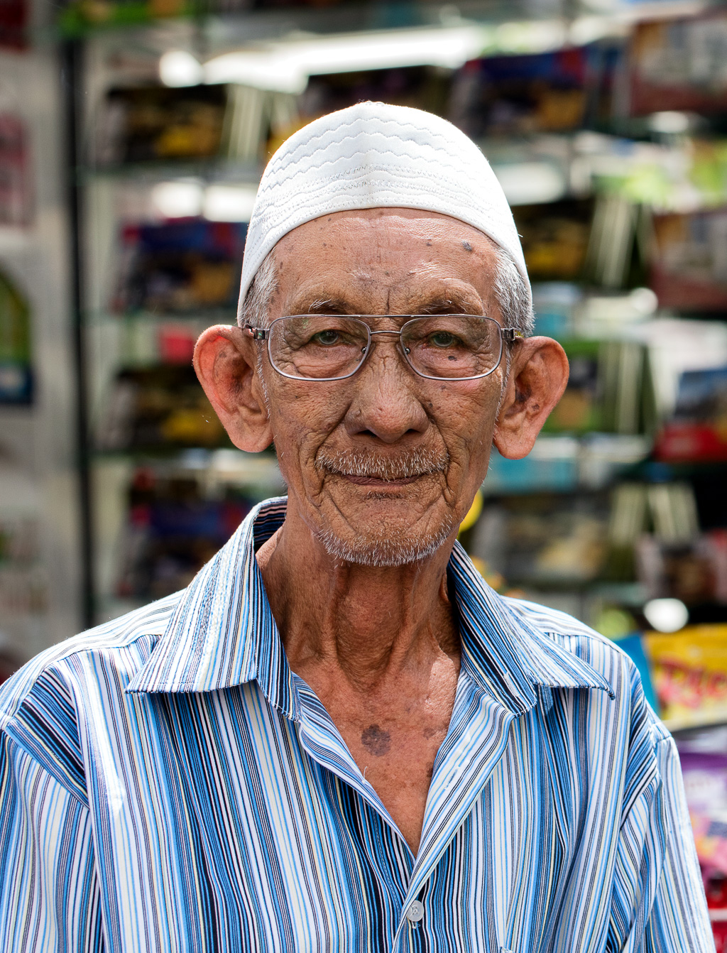 Portrait of elderly man wearing glasses and white cap