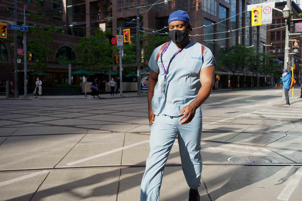 Health care worker in hospital greens crosses the street