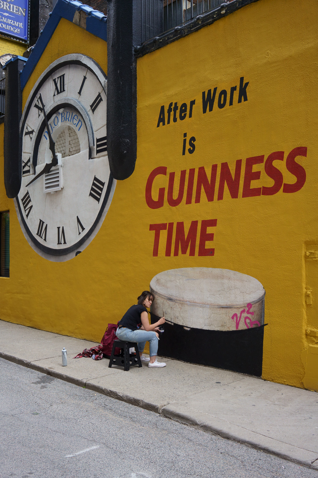 A woman retouches a painting of a pint of Guinness on the wall of the P.J. O'Brian Pub in Toronto.