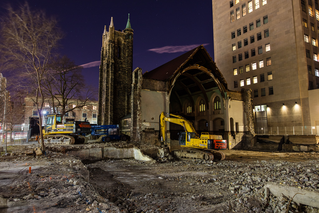 Night photograph of a backhoe behind the remnants of a demolished church.