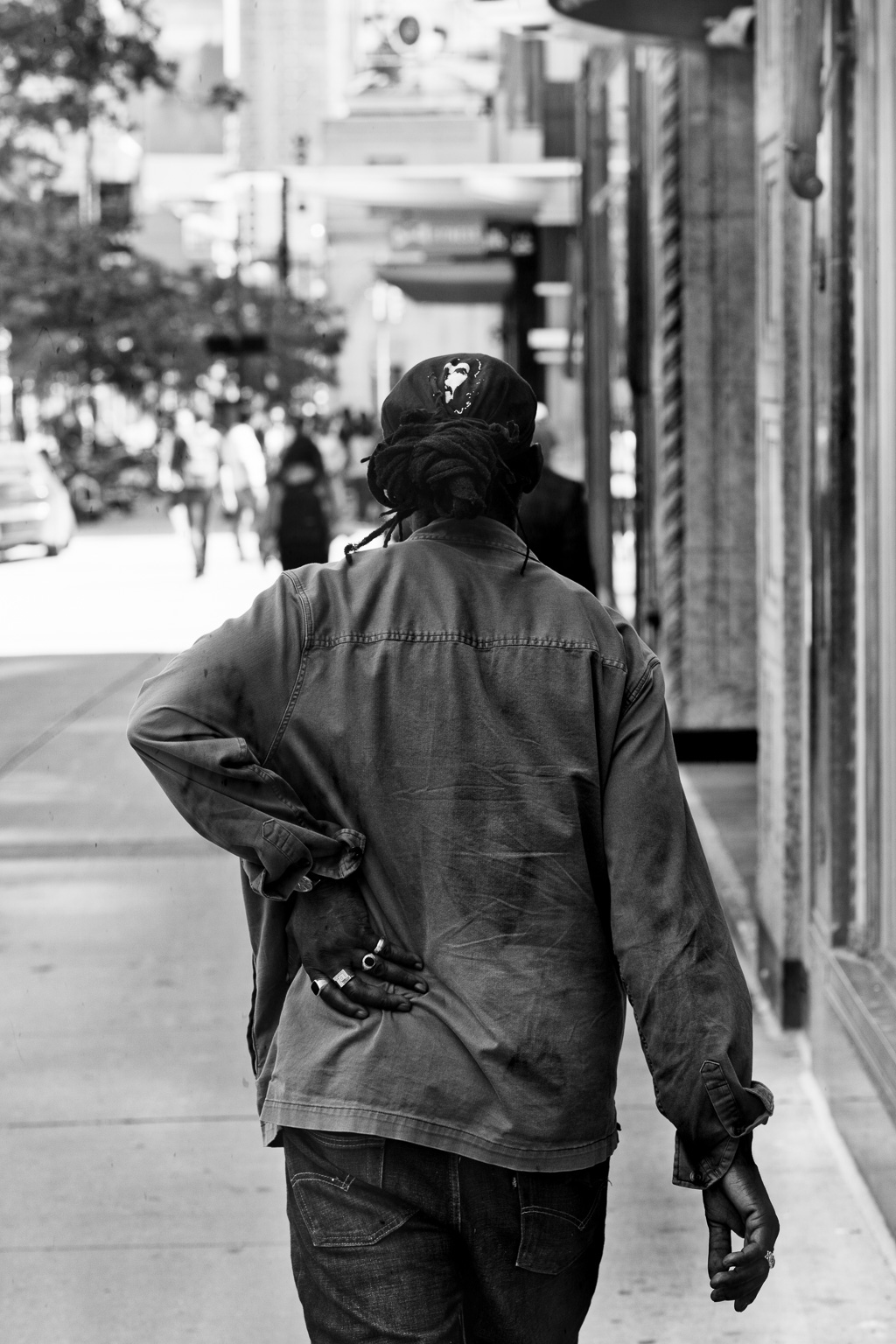 A man walks south down Yonge Street with his left hand pressed to his hip.