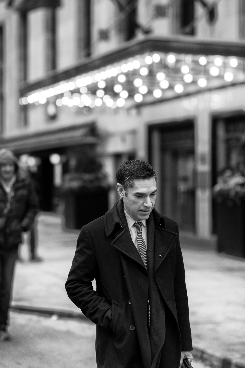 Man in tie and overcoat walks past the west entrance of Toronto's Fairmont Royal York Hotel.