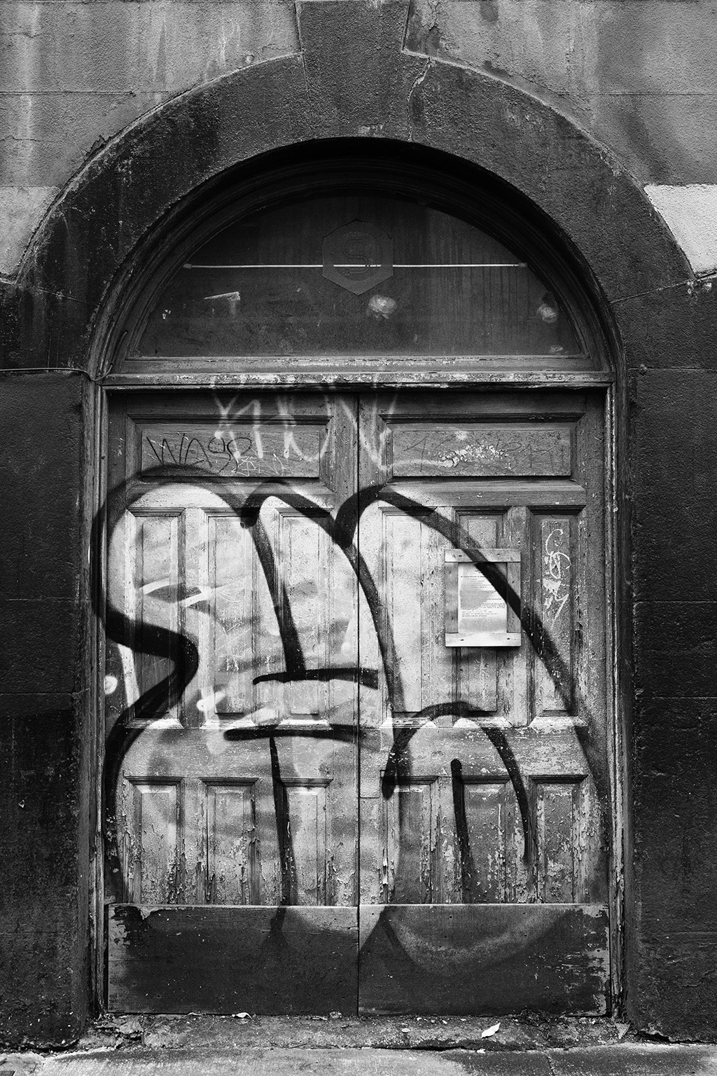 A black and white photograph of a graffiti-covered double door in Dublin.