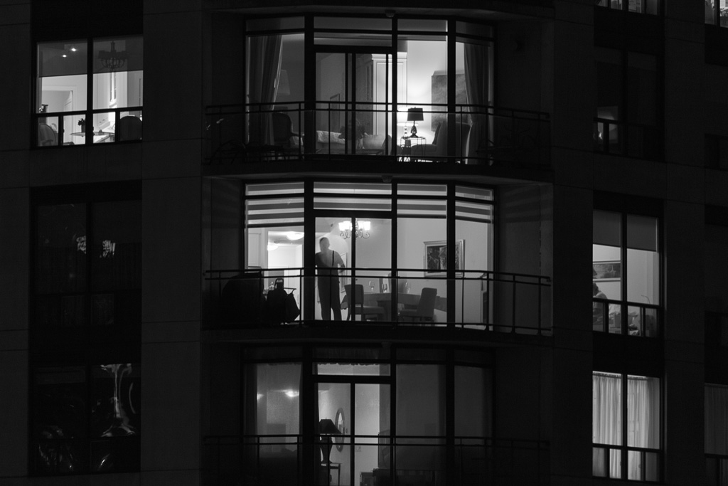 Voyeuristic night view of people in condominium units.