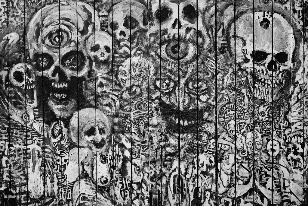 Black and white painting of skulls and hellish faces on fence in Toronto's Kensington Market