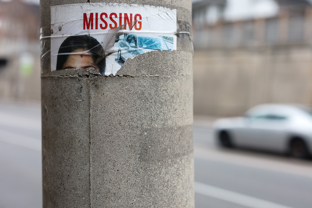 Torn missing person poster on a utility pole