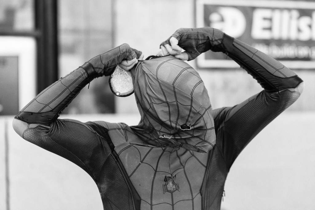 Spiderman struggles to line up the eye holes of his mask