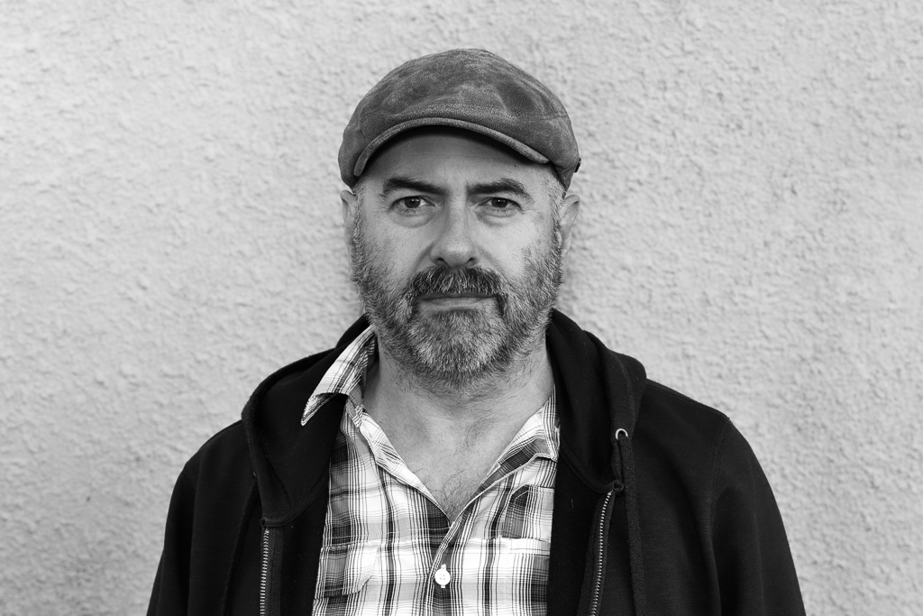 Black and white portrait of a bearded man wearing a cap.