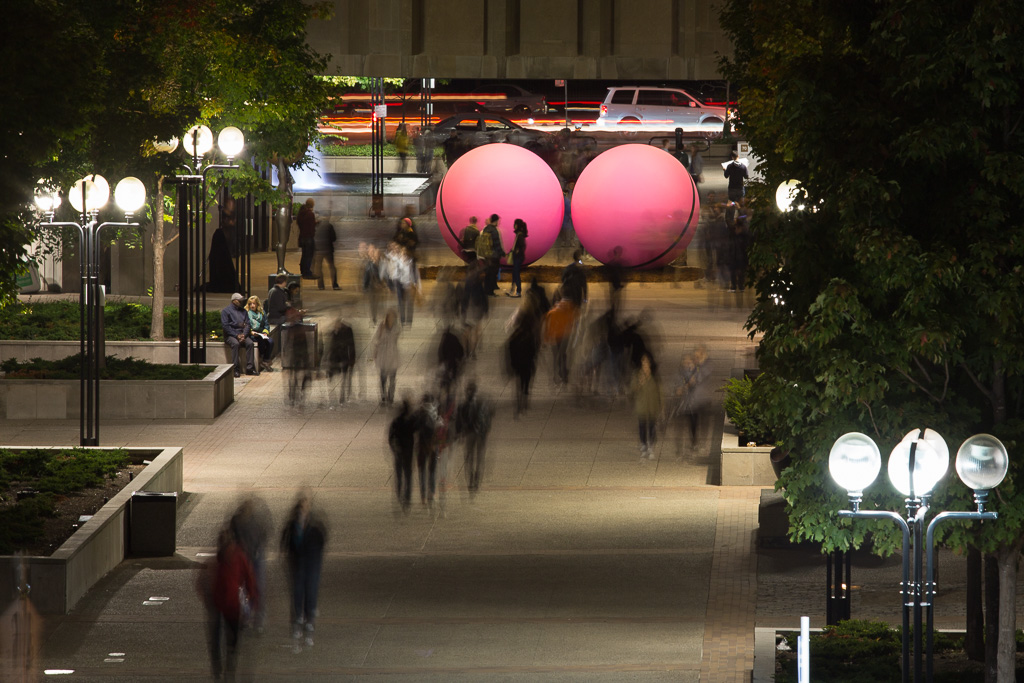 Night photograph of a sculpture called Pair, by Neil Campbell, at the 2012 Nuit Blanche in Toronto. Pair is a pair of giant pink balls sitting underneath the court house library on University Avenue.