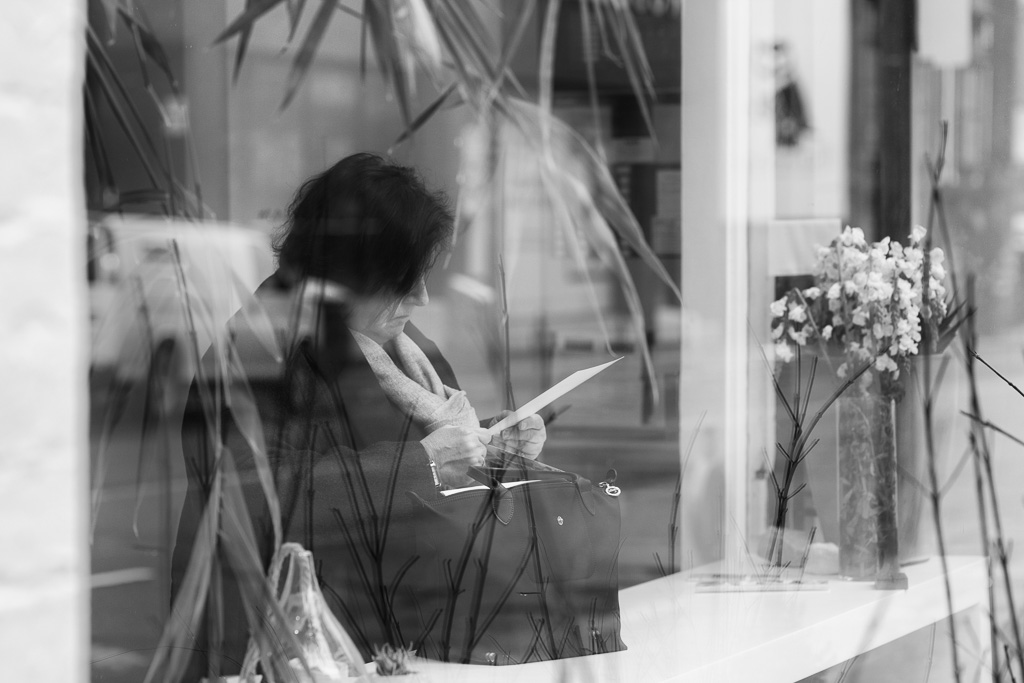 A woman sits in a window reading a note.